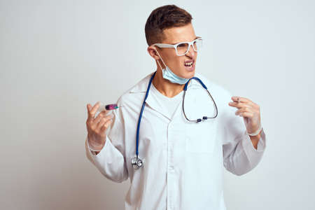 doctor in a medical gown with a stethoscope and glasses on a light background cropped view portraitの写真素材