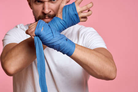 Sporty man in a white T-shirt boxing bandages on the hands of a workout lifestyle pink backgroundの写真素材