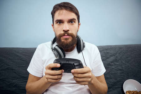 A man sits on a sofa with a gamepad in his hand. Leisure lifestyle game consoleの写真素材