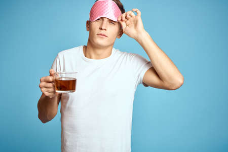 man with pink sleep mask and cup of tea drink cheerfulness model breakfastの写真素材