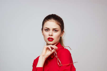 fashionable woman in a red shirt on a light background fun emotions bright makeup glasses attractive...