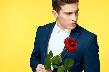 Gentlemen in classic suit on yellow background and red rose romance cropped view model portrait.の写真素材
