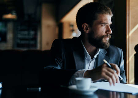 business man sitting at a table in a cafe documents work official coffee cupの写真素材