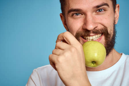 An energetic man with a green apple on a blue background gestures with his hands Copy Space emotionsの写真素材