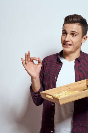 Man eating wooden pallet fast food french fries hamburger diet food restaurant light backgroundの写真素材