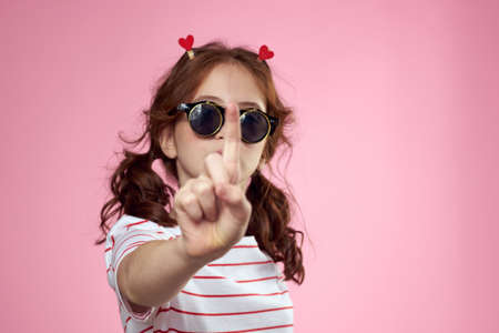 Cute girl sunglasses striped t-shirt lifestyle fun style pink backgroundの写真素材