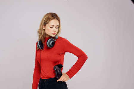 Woman with headphones controller in hands a console game fun leisure red jacket lifestyle light backgroundの写真素材
