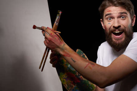 A man with a palette in his hands brush easel art Creative approach hobby dark backgroundの写真素材