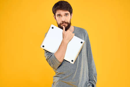 man with laptop wireless technology internet lifestyle work yellow isolated backgroundの写真素材