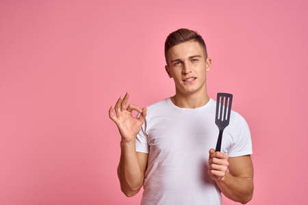 Man with kitchen tools on pink background spatula for cooking model cropped viewの写真素材