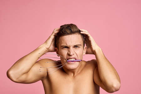 Nude man with head massager on pink background emotions model beautiful faceの写真素材