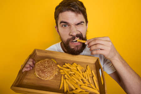 Man with wooden pallet fast food hamburger french fries diet food intake close-upの写真素材