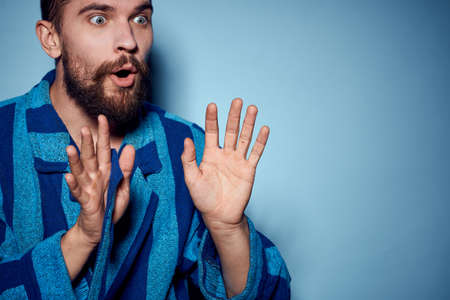 A man in a blue robe on a light background gestures with his hands model home clothesの写真素材
