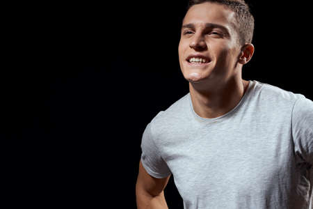 handsome man in white t-shirt on black background inflated arm muscles sport model cropped view Copy...