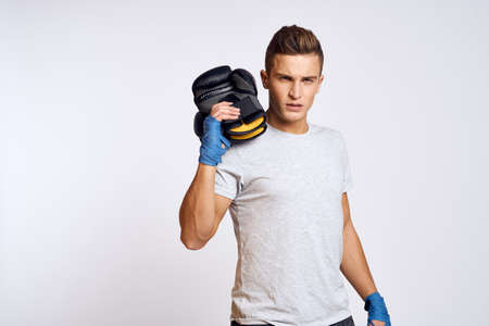 Strong man with boxing gloves and in a white t-shirt on an isolated background cropped view of the...