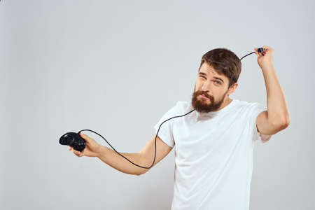 A man with a joystick in his hands fun games lifestyle white t-shirt light backgroundの写真素材