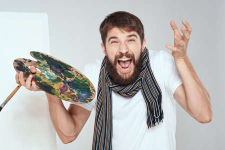 The artists palette and in the hands of an easel art hobby scarf around the neck a light background