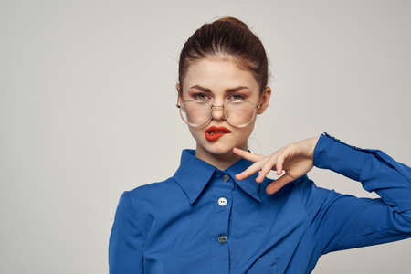 Portrait of emotional woman in blue shirt and glasses bright makeup model light background cropped view Copy Spaceの写真素材
