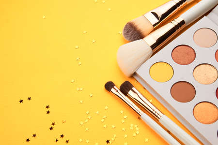 Professional eyeshadows and makeup brushes on a yellow background make-up decorationの写真素材
