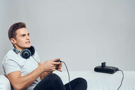 A man sits on the couch with headphones a video game set-top box entertainment fun
