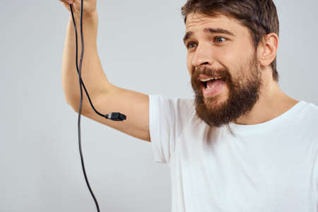 A man with a joystick in his hands fun games lifestyle white t-shirt light backgroundの写真素材