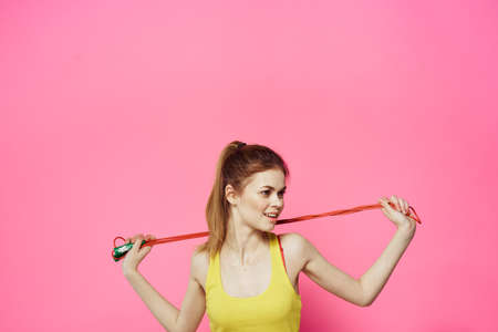 Sportive woman jumping rope friend exercise yellow tank top workout pink background