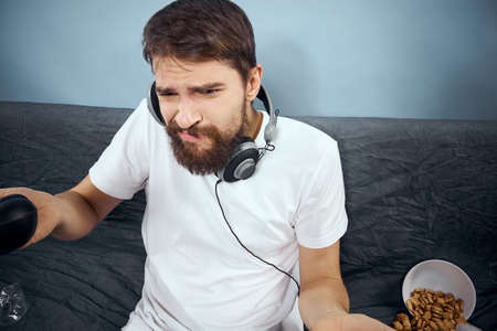 A man sits on a sofa with a gamepad in his hand. Leisure lifestyle game console