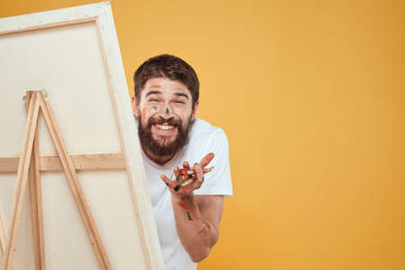 Male artist stands in front of easel emotions drawing Creative approach yellowの写真素材