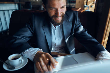Business man sitting in a cafe in front of a laptop with a cup of coffee work technology lifestyleの写真素材