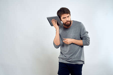 A man with a tablet in his hand internet technology communication gray jacket light backgroundの写真素材