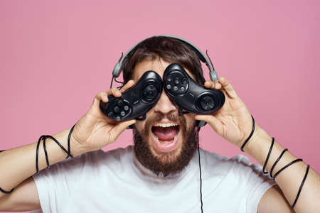 Man in headphones with joysticks in hands playing games lifestyle fun entertainment pink backgroundの写真素材