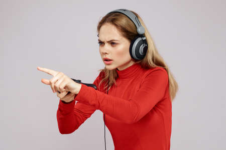 Woman with headphones Joystick in hands playing games fun leisure lifestyle entertainment red shirt gray backgroundの写真素材