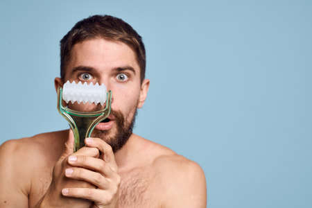 Man with naked shoulders body massager Skin care blue backgroundの写真素材
