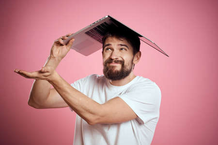 cheerful man with an open laptop on his head on a pink background cropped view Copy Space
