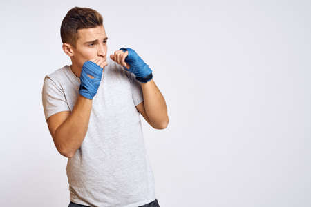 sporty male boxer in blue gloves practicing punches on a light background cropped viewの写真素材