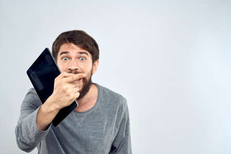 emotional man holding tablet technology communication internet work light backgroundの写真素材