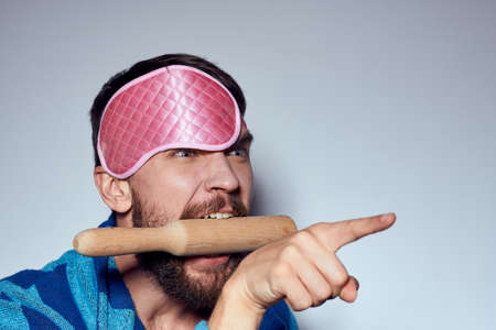 a man in a pink sleep mask holds a rolling pin in his hands and emotions energy aggression model...