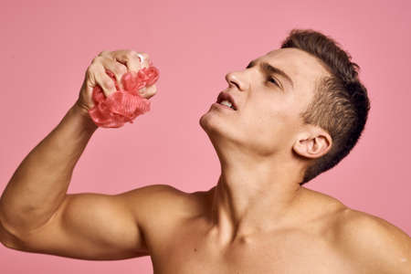 Nude man with a washcloth in his hand on a pink background cropped viewの写真素材