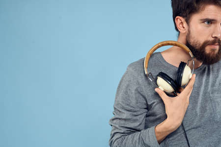 Man with headphones in hands music emotion technology lifestyle fun blue background close-upの写真素材