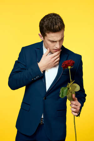 Gentlemen in classic suit on yellow background and red rose romance cropped view model portrait.の写真素材