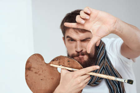 The artists palette and in the hands of an easel art hobby scarf around the neck a light backgroundの写真素材