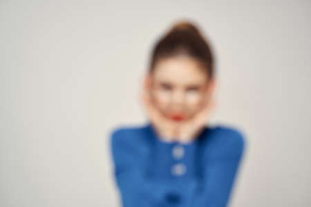 Portrait of emotional woman in blue shirt and glasses bright makeup model light background cropped...