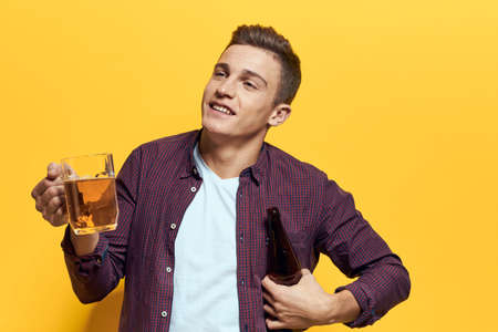cheerful man mug of beer with bottle fun drunken lifestyle alcoholic yellow backgroundの写真素材