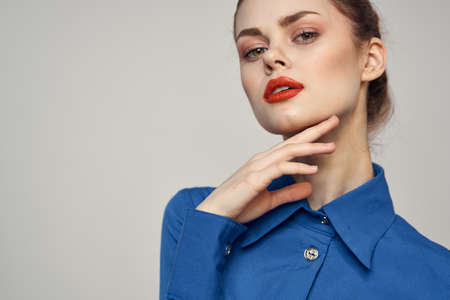 Portrait of a beautiful woman with red lips on a light background and a blue shirt cropped view