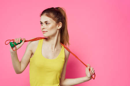 Sportive woman jumping rope friend exercise yellow tank top workout pink background
