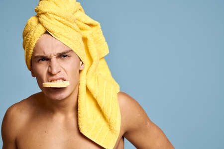 A man with a yellow towel on his head and a soft sponge for cleansing the skin cosmetology modelの写真素材