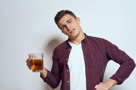 Drunk man with a mug of beer vacation alcohol lifestyle in a red shirt emotions light backgroundの写真素材