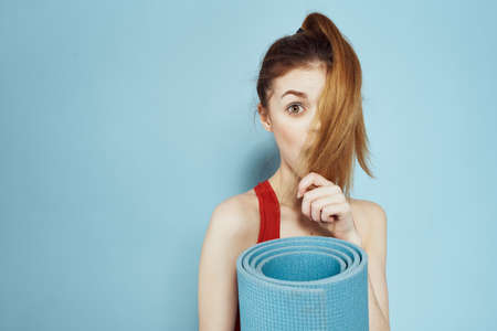 Sportive woman in red tank top mat for workout exercises lifestyle blue backgroundの写真素材