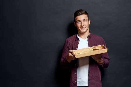 man holding wooden pallet with fast food in his hands diet food hunger lifestyle dark background