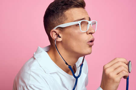 young doctor with a stethoscope and glasses on a pink background nurse interns model